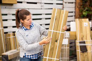 Wahl der Holzart. Frau mit Holzzaun-Teilen in der Hand